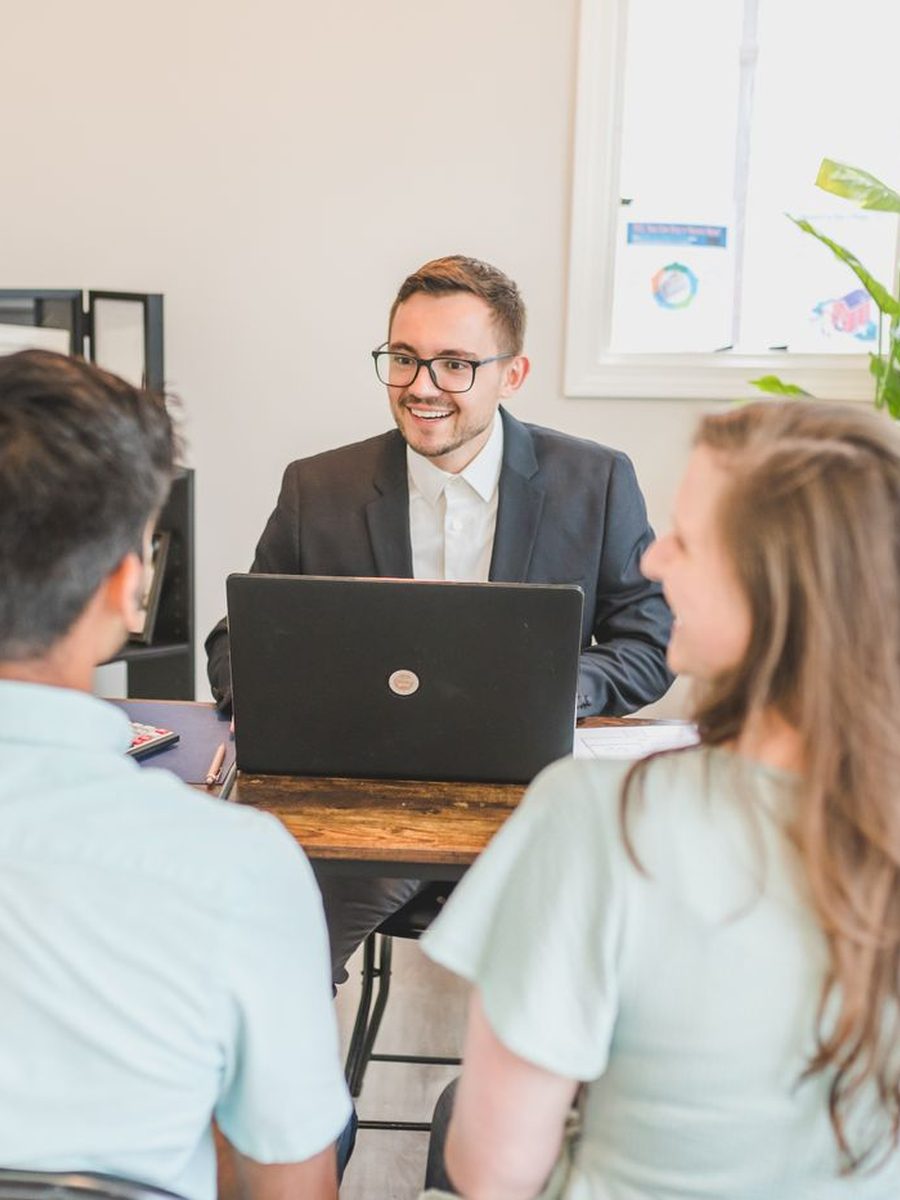 An insurance agent in a suit meeting with a couple in his office